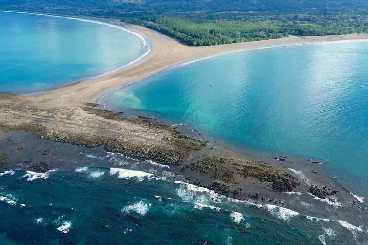 Luchtfoto van een zandbank in de vorm van een walvisstaart die de oceaan in loopt.